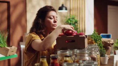Çevre dostu sıfır atık süpermarketindeki vejetaryen kadın elmaları sayıyor ve onları alışveriş sepetine ekliyor. Mahallenin bakkal dükkanındaki müşteri özenle toplanmış meyve topluyor.
