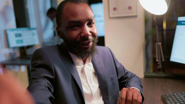 Afrikalı Amerikalı iş adamı, günlük şirket dahili görevlerinin videosunu çekmek için selfie modunda akıllı telefon kullanıyor. İş yerindeki çalışanın iş bilgilerini açıklarken kendini kameraya çekmesi.