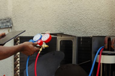 Aşırı soğutucu, nem sızıntısı ve diğer sorunları tespit edebilen profesyonel manifold göstergelerini kapatın. Basınç seviyelerini okumak için manifold ölçer kullanan yetenekli bir işçi.