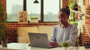 Afro-Amerikalı bir kadın evde blog yazısı yazıyor, gün batımını seyrediyor ve teslim tarihinden önce günlük işleri hallediyor. Bağımsız olarak online kariyer geliştirmeye çalışan kişi, becerilerini geliştirmeye çalışıyor..