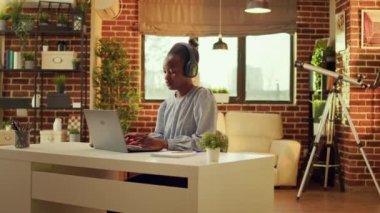 Freelancer müzik dinlerken ve internet aktiviteleri yaparken çalışma istasyonunda çalışmaktan hoşlanıyor. Günbatımında, Afrikalı Amerikalı kadın blogda birden fazla iş yapıyor, online kariyeri var..