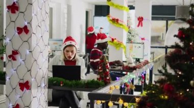 Noel Baba şapkası takan çalışanlar Noel 'in gecikmiş bir döneminde süslü ofiste çalışıyorlar. Çeşitli işyerlerindeki çalışkan personel kırmızı xmas çelenkleri ve fiyonklarla süslenmiş.