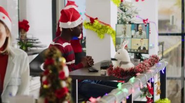 İnternette çalışan bir işçi Noel süslemeli ofiste müdürlerin değerlendirmelerini dinliyor. Uzak telekonferans personeli, xmas sezonu boyunca yönetim yöneticilerinden geri bildirim alıyor