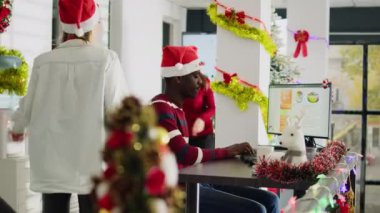 Noel sezonunda şenlik süsleme ofisinde proje için fikir üreten iş arkadaşlarının görüntülerini büyüt. Çok kültürlü işyerindeki işçiler xmas ağacı ve çelenklerle süsleniyorlar