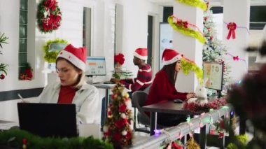 Çalışkan çok kültürlü çalışanlar Noel sezonu boyunca süslü püslü ofislerde çalışıyorlar. Çalışkan BIPOC çalışanları çeşitli xmas 'lardaki bilgisayarlara veri yüklüyorlar