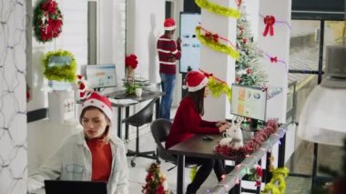 Asyalı personel Noel döneminde süslü ofiste çalışıyor, denetleyici denetim sürecini gösteriyor. Tatil sezonunda çeşitli ksenlerdeki muhasebe çözme görevi