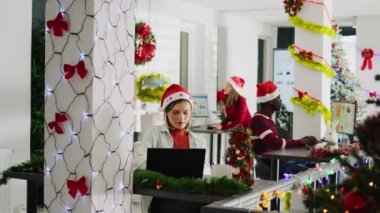 Süslü ofiste Noel sezonunda çalışan mutlu etnik gruplar. Neşeli çalışanlar kış şenliği sırasında çeşitli iş yerlerinde meslektaşlarının yanında masa başında görevleri çözerler.