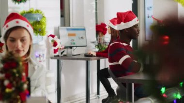Dost canlısı Afro-Amerikan girişim çalışanının portresi süslü ofiste noel sezonu üzerinde çalışıyor. Kış bayramı boyunca, çok ırklı iş yerlerindeki iş yerlerindeki görevleri çözen işçiler