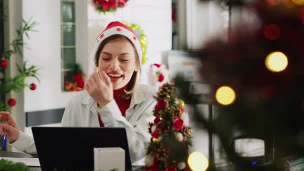 クリスマスの女性は シフト休憩中にオフィスのビデオ会議の友人を装飾しました 冬のホリデーシーズン中にオンラインコールで話すXmasの装飾で飾られたワークスペースの従業員 — ストック動画