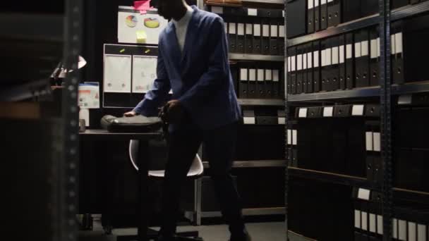 アフリカ系アメリカ人探偵がアーカイブ ルームで 証拠やファイルを見直し 技術に依存している 警察官が法医学捜査とバックグラウンドチェックを行い 正義が輝く — ストック動画