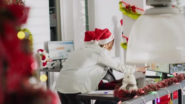 アフリカ系アメリカ人の従業員は 同僚の助けを求めるクリスマスオフィスで働いています Xmas Adornの職場のコンピュータ スクリーン上の財務図を見ている会社の人員 — ストック動画