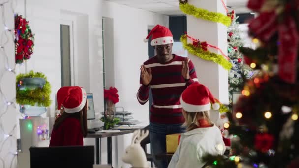 非洲裔美国人雇员戴着圣诞礼帽 在休息时装模作样 以此招待同事 在秘密圣诞晚会上玩哑剧的同事 — 图库视频影像