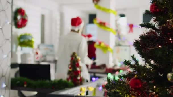 お祝いの装飾オフィスでクリスマスシーズン中にプロジェクトのためのアイデアをブレインストーミングする従業員を撮影したズーム Xmasライトとガーランドで飾られた多文化職場の労働者 — ストック動画
