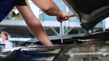 Araba servisinde sertifikalı tamirci tarafından araç parçalarını tamir ettikten sonra cıvataları sıkmak için kullanılan tork anahtarına yakın çekim. Tamirci otomobili tamir etmek için profesyonel araçlar kullanıyor.