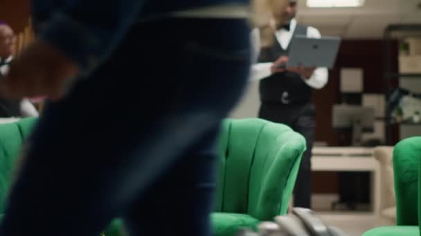 专注的酒店经理坐在大堂的笔记本电脑上 盯着屏幕 跟踪预订情况 以管理预订 酒店业的男仆穿着制服工作 手持射击 — 图库视频影像