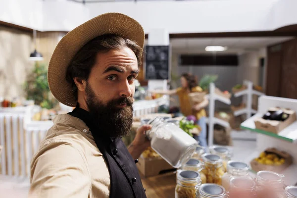 Zero waste shop entrepreneur using selfie camera on cellphone to show his natural chemical free products online. Supermarket owner promoting sustainable lifestyle, presenting his merchandise