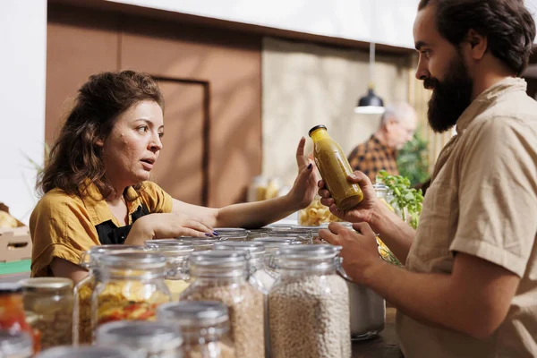 Farmer showcasing her products in zero waste marketplace venue, trading additives free food to interested customer. Local seller selling natural sustainable bulk products during event to client