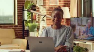 Ilık odada serbest çalışan birinin portresi masa başında online proje görevleri üzerinde çalışıyor, evdeki aktiviteleri uzaktan çözüyor. Blogcu işi olan Afrikalı Amerikalı kadın, serbest meslek.
