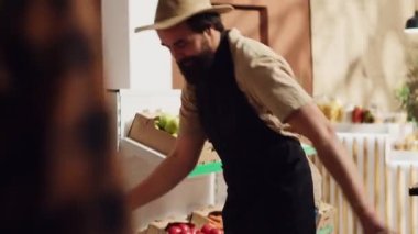 Yeni açılan plastik ücretsiz sıfır atık süpermarketinde ilk müşterileri karşılayan tedarikçi, kırmızı kurdeleyi kaldırıyor. Tüccar, tüketicileri sürdürülebilir çevre dostu mahalle mağazasında karşılıyor.