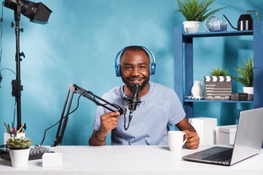 İnternet kanalında mikrofona konuşan, kulaklıkla gülümseyen bir vlogger. Mikrofonla konuşan, web içeriği yaratan ve podcast portresi kaydeden bir blog yazarı