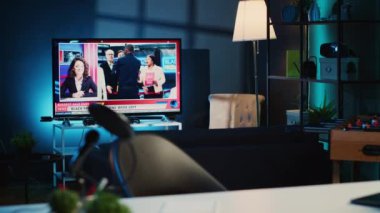 Kara Cuma haberlerinin yayınlandığı loş bir apartman dairesinde gece televizyon açık kaldı. Oturma odasında lamba gölgesiyle aydınlatılmış televizyon raporlarını gösteren ev eğlencesi sistemi