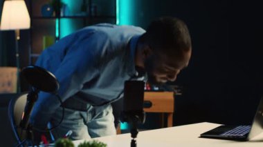 İçerik yaratıcı, akıllı telefon kamerasıyla çevrimiçi yayın platformları için video kaydetmek üzere loş ışıklı stüdyoya geliyor. Etkilenen kişi hayran kitlesini karşıladı, cep telefonunu kullanarak görüntüleri kaydetti