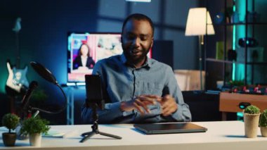 Afrikalı Amerikan teknolojisi internet yıldızının yeni yayınlanan oyun dizüstü bilgisayarını görüntülemesi, seyirciyi selamlaması ve onlara özellikler hakkında geri bildirim sunması, destek vermesi.