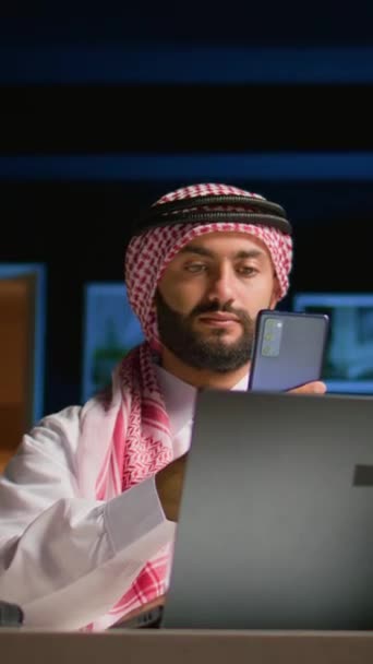 インターネット上のビデオ会議中に海外在住の友人をチェックする垂直ビデオアラビア人男性 ムスリムは 同時にオンラインビデオ通話セッションで仲間と一緒に時間を楽しんでいます — ストック動画