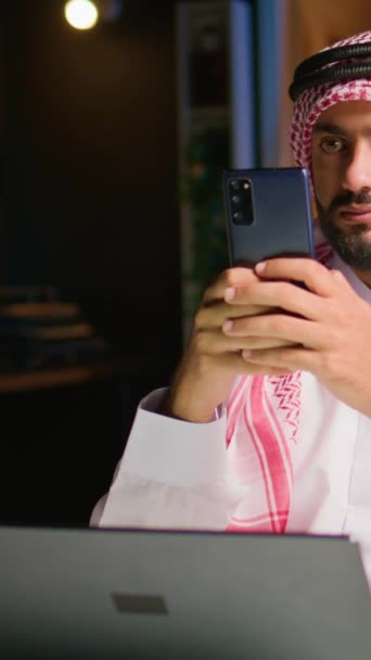 Vertikales Videoporträt Eines Glücklichen Arabischen Telearbeiters Der Sms Freunde Sendet — Stockvideo