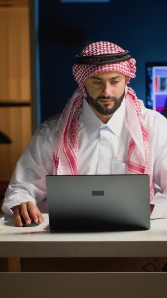垂直ビデオアラブのビジネスマンは ラップトップにタイピングし 自宅に滞在しながらネットサーフィン プロのビジネス環境で電子メールを介して会話するムスリム男性 さまざまなタスクの解決に焦点を当てた — ストック動画
