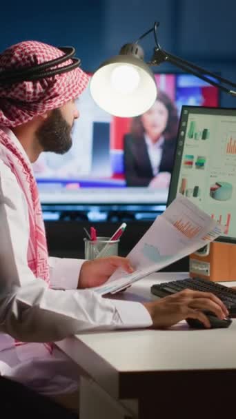 在公寓办公室远程工作时 垂直视频阿拉伯远程工作者检查分析数据集 以电视为背景噪声的公司关键性能指标优化 — 图库视频影像