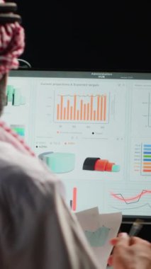 Dikey video odaklı işadamı dairede uzaktan çalışırken analitik istatistiksel verileri kontrol ediyor. Anahtar performans göstergelerini optimize eden şirket yöneticisi, yakın çekim