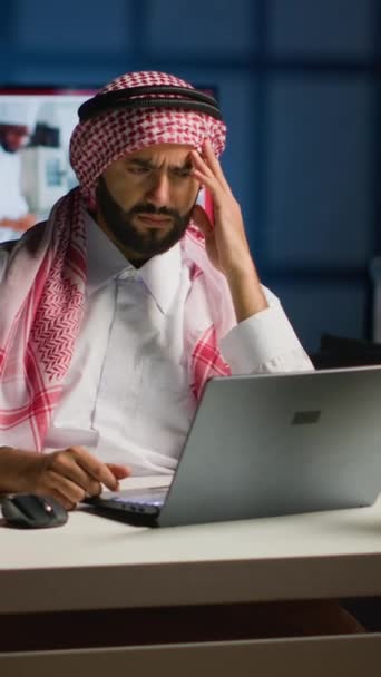 垂直录像阿拉伯商人在家里工作时患有偏头痛 他在私人公寓办公室里使用笔记本电脑 自营职业的中东男人回答因过度工作而头疼的电子邮件 — 图库视频影像