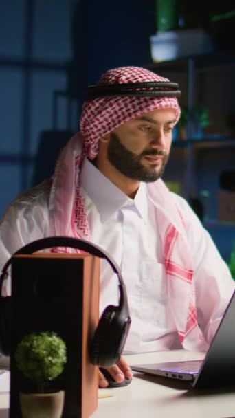 垂直视频快乐的Arab远程工作者在舒适时尚的公寓里工作 在笔记本电脑上写电子邮件 在家打字数据的中东员工 检查设备上的公司信息 — 图库视频影像