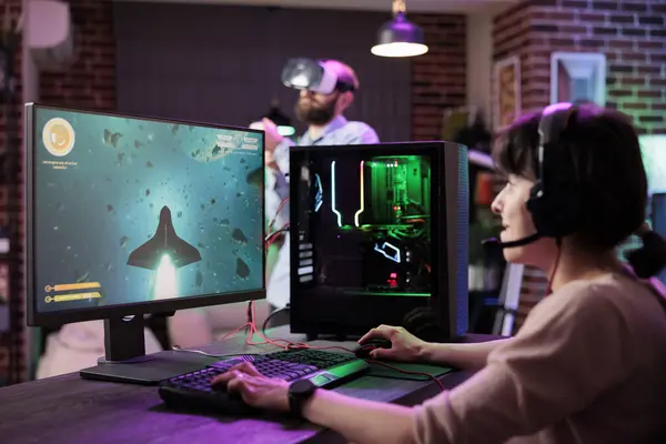 Professional gamer engaging in online competitive multiplayer tournament using cutting edge PC, captivating viewers during live stream. Woman in rgb lights lit home playing videogames