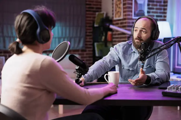 Show host interviewing guest during live stream, talking about fashion and style trends. Man discussing with social media influencer, recording episode for online podcast
