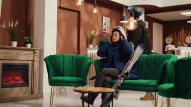 Dağlık oteldeki arkadaşlar spor giysileri giyip karlı yamaçlardan aşağı inmeden önce kayak ya da snowboard ekipmanlarını kontrol ediyorlar. Atletik çift lobideki kanepede boş zaman aktivitelerini bekliyor..