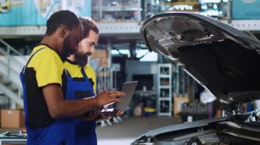 Araba servisindeki vasıflı tamirciler, hasarlı araç için dizüstü bilgisayar ve tablet kullanarak yeni parçalar sipariş ediyorlar. Bozuk arabalardaki eski parçaların yerine yenilerini arayan meslektaşlar