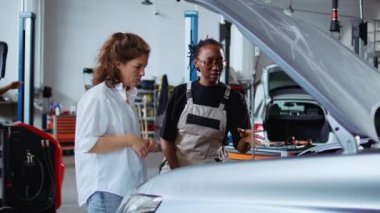 Garajda çalışan eğitimli bir tamirci müşteri için araba tamir ediyor, araç kaputunun altını iyice kontrol ediyor. Otomobil tamirhanesinde müşteri otomobilinin yıllık bakımını yapan Afrikalı Amerikalı bir uzman.