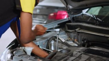 Araba servisindeki hassas tamirci, araç parçalarını tamir ettikten sonra fındık sıkmak için İngiliz anahtarı kullanıyor. Otomobilin arızasız çalıştığından emin olmak için profesyonel araçları kullanan tamirci çalışanı, kapatın