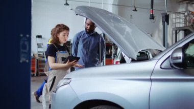 Garajda lisanslı uzman. Aracın bakımını yaparken dizüstü bilgisayarla takip ediyor. Müşteriyle konuşuyor. Araba servisindeki tamirci otomobili kontrol ediyor.