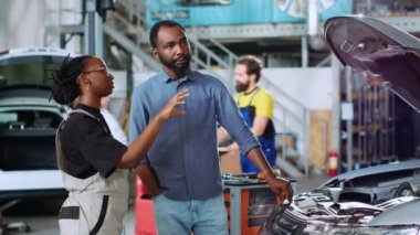 Otomobil tamirhanesinde, Afro-Amerikan bir adamın araba parçalarını görselleştirmek için artırılmış gerçeklik hologramını kullanıyor. İşçi, AR holografik teknolojisini kullanarak istemci araç hasarlarını gösterir