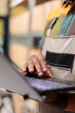 Depo müdürü müşterilerin siparişlerini hazırlamaya başlamadan önce dizüstü bilgisayardaki kargo hisselerine bakıyor, nakliye detaylarını kontrol ediyor, dağıtım departmanında çalışan personel, dağıtım merkezi kavramı.