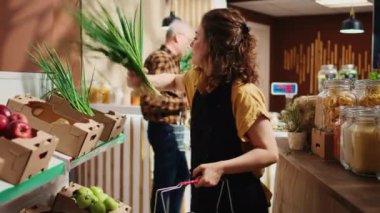 Çalışkan çevre dostu market çalışanı rafları yeni toplanmış sebzelerle dolduruyor. Mahallenin süpermarketinde organik sebzeler sergileniyor.