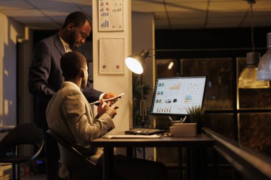 Şirket çalışanları finansal grafikleri analiz ederek şirket stratejisini başlangıç ofisinde tartıştıklarını rapor ediyorlar. Yönetici yöneticiler iş kârını artırmak için yatırım planında fazla mesai yapıyorlar