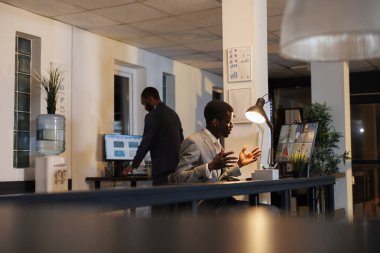 Yetkili yönetici, online video görüşmesi sırasında uzaktaki iş arkadaşlarına finansal yatırım grafiğini açıklıyor. Çeşitli uzaktan kumanda ekipleri gece geç saatlere kadar şirket stratejisinde çalışıyor.