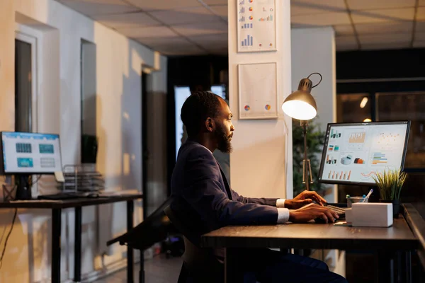 美国黑人工人在电脑上分析营销统计数据 打字公司的战略 站在创业办公室的办公桌前 企业家加班在最后的报告 业务概念 — 图库照片
