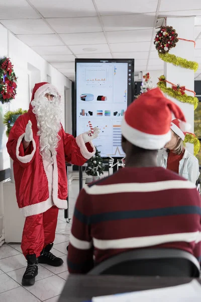 サンタクロースとして着飾られたモチベーションスピーカーは お祝いの装飾オフィスでキャリアを進めるために労働者にインスピレーションを与えます Xmasホリデーシーズン中にコーポレートスキルを習得するコワーキングミーティング参加者 — ストック写真