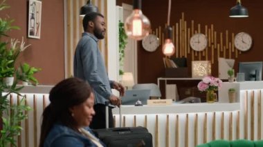 Gezgin resepsiyonda servis ve oda kartı istiyor resepsiyondaki resepsiyonisti aramak için zili çalıyor. Bagajlı Afrikalı Amerikalı bir adam otel konaklama izni istiyor. El kamerasıyla..