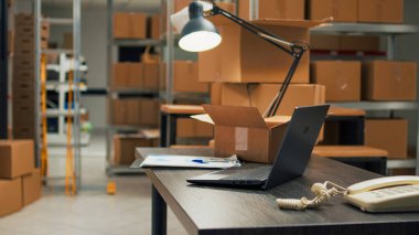 Empty warehouse with office space to work on inventory and logistics, storage room filled with stacks of cardboard boxes on shelves. Storehouse space with racks, quality control on merchandise.